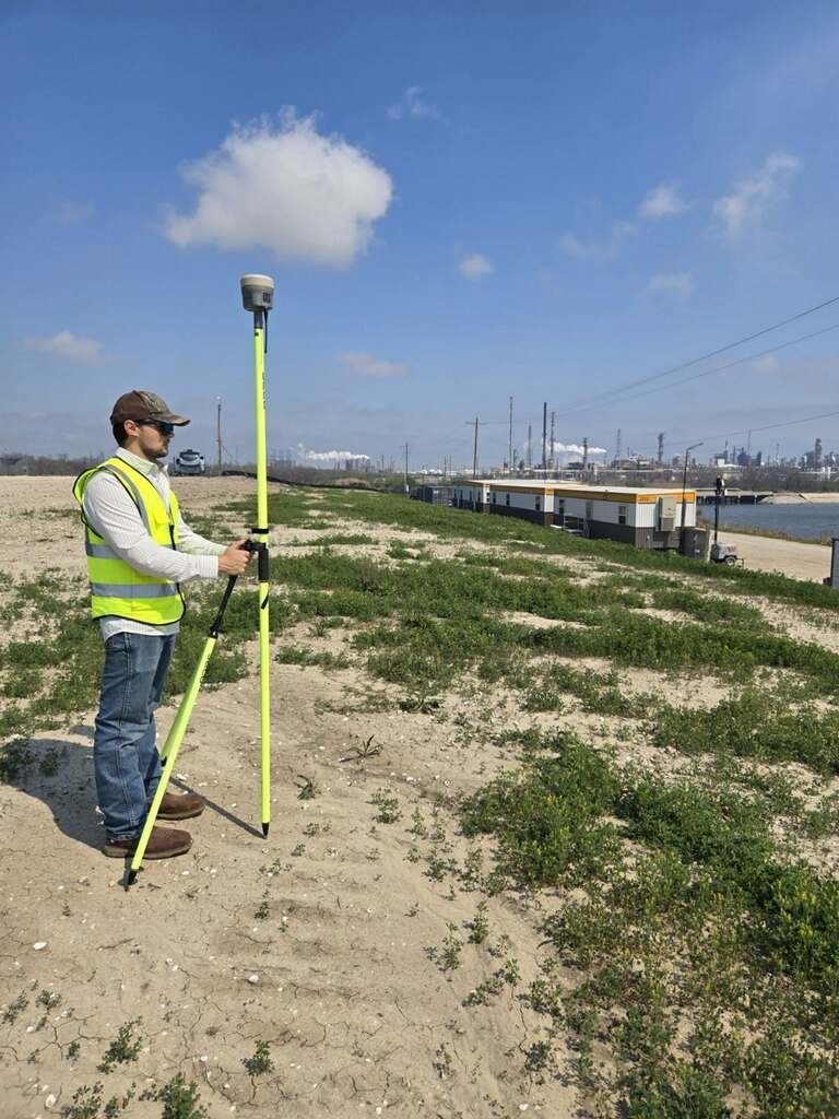 A field worker collecting location data near a waterfront site.